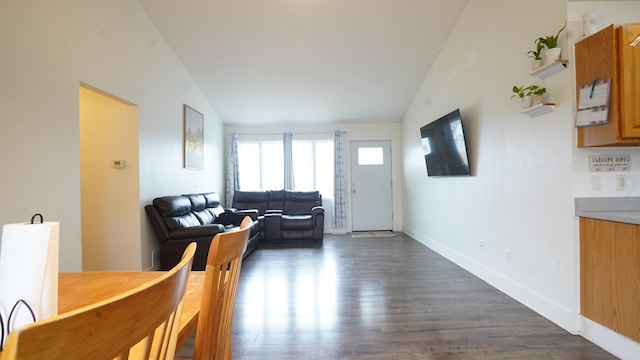 living room featuring lofted ceiling, dark wood-type flooring, and baseboards