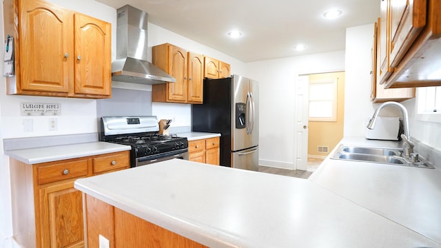 kitchen with stainless steel appliances, visible vents, light countertops, a sink, and wall chimney range hood