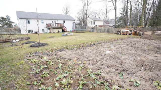 view of yard with a deck, a trampoline, and a fenced backyard