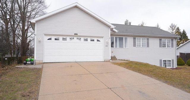 single story home with a garage, concrete driveway, and fence