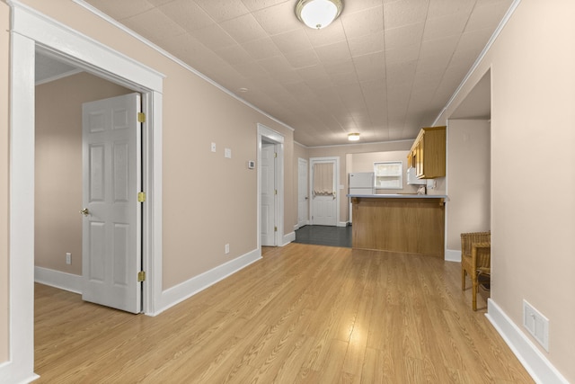 unfurnished living room featuring light wood-style floors, visible vents, ornamental molding, and baseboards