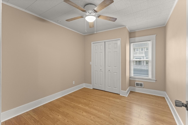 unfurnished bedroom with ornamental molding, light wood-style flooring, visible vents, and baseboards