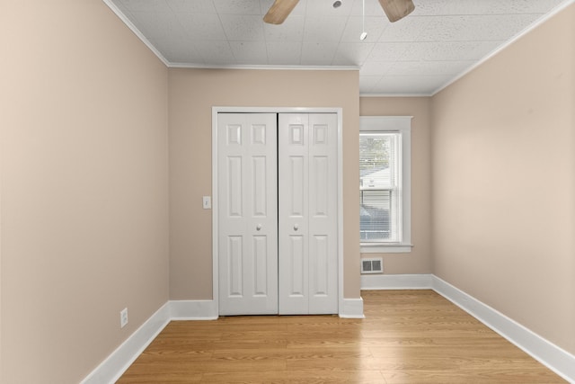 unfurnished bedroom featuring light wood-style floors, crown molding, visible vents, and a closet