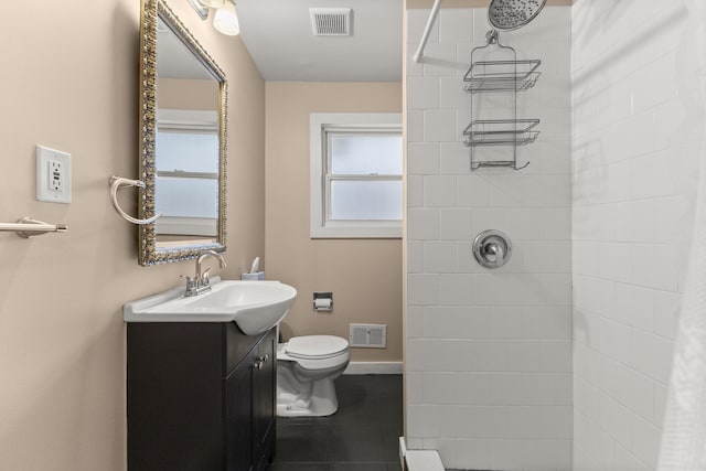 bathroom with toilet, visible vents, a tile shower, and vanity