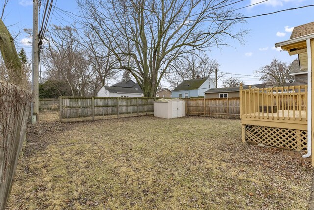 view of yard with a shed, a wooden deck, a fenced backyard, and an outbuilding