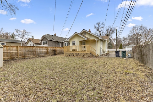 rear view of house with a fenced backyard, a lawn, and a wooden deck