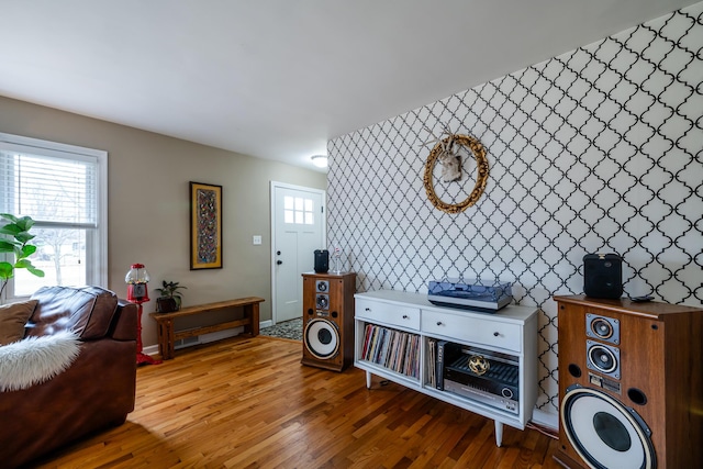 interior space with a wealth of natural light, wallpapered walls, an accent wall, and wood finished floors