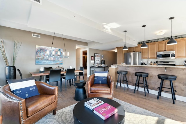 living room featuring a chandelier, visible vents, and light wood-style flooring