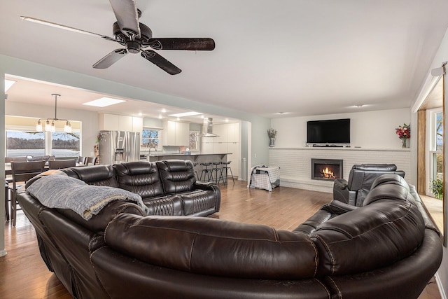 living area featuring light wood-style floors, a fireplace, and a ceiling fan