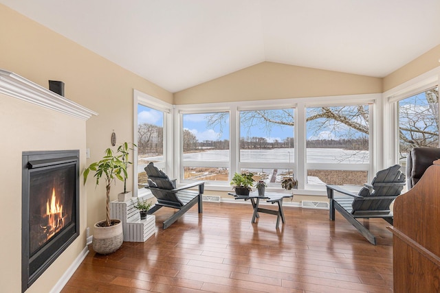 sitting room with lofted ceiling, hardwood / wood-style flooring, visible vents, and a glass covered fireplace