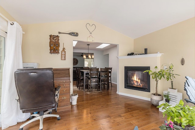 office area featuring a glass covered fireplace, vaulted ceiling, and wood finished floors