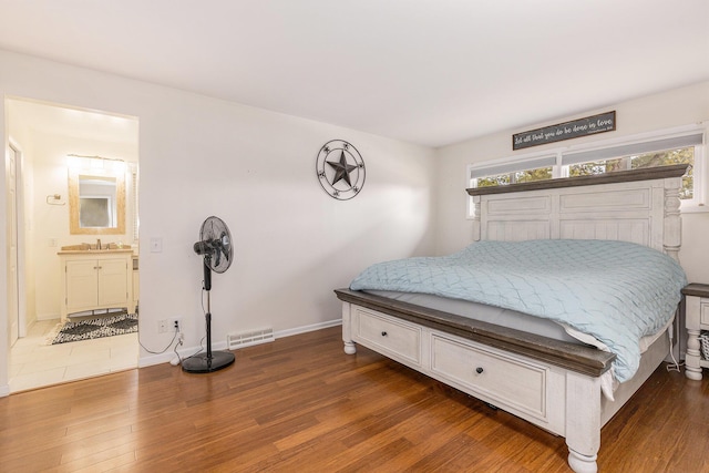 bedroom featuring a sink, multiple windows, visible vents, and wood finished floors