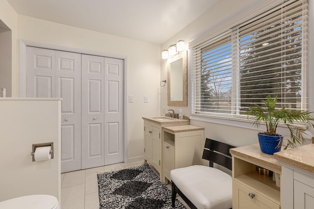 bathroom featuring a closet, toilet, vanity, baseboards, and tile patterned floors