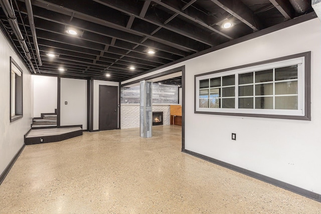 finished basement featuring a warm lit fireplace and baseboards