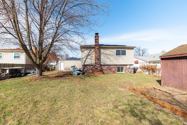 22273 Collette St, Woodhaven, MI 48183 - rear view of house with fence, solar panels, a chimney, and a lawn
