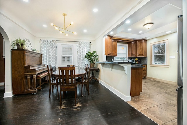 dining space with baseboards, arched walkways, wood finished floors, and recessed lighting