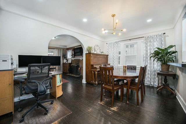 dining area featuring plenty of natural light, arched walkways, a brick fireplace, and dark wood finished floors