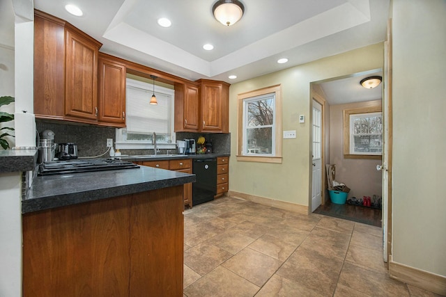 kitchen featuring a sink, black dishwasher, backsplash, dark countertops, and a raised ceiling