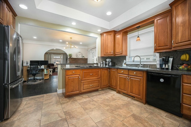 kitchen with arched walkways, appliances with stainless steel finishes, a sink, and brown cabinets