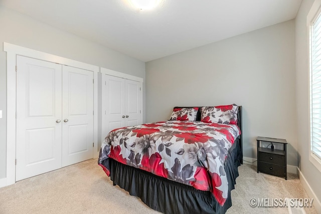 carpeted bedroom with multiple windows, baseboards, and multiple closets