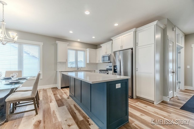 kitchen with decorative backsplash, a center island, an inviting chandelier, stainless steel appliances, and white cabinetry