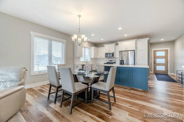 dining space with light wood-style floors, recessed lighting, baseboards, and an inviting chandelier