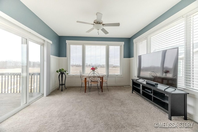 interior space with a healthy amount of sunlight, ceiling fan, carpet floors, and wainscoting