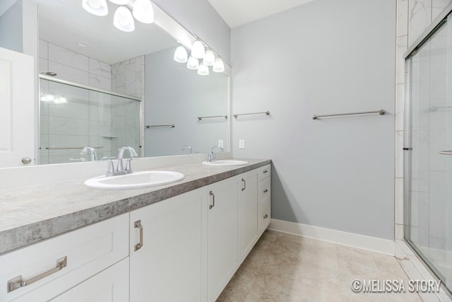 bathroom featuring a stall shower, a sink, baseboards, and double vanity