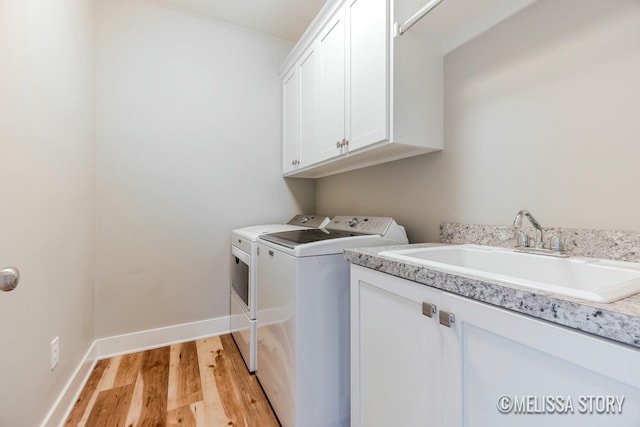 laundry room featuring cabinet space, a sink, light wood-type flooring, independent washer and dryer, and baseboards