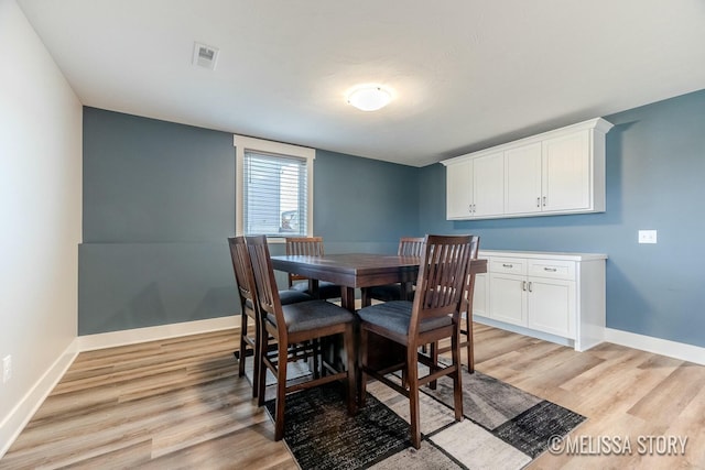 dining room with light wood finished floors, visible vents, and baseboards