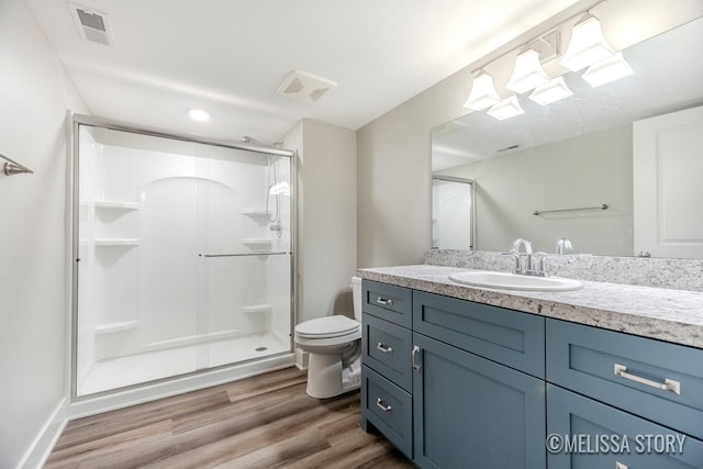 full bathroom featuring visible vents, toilet, wood finished floors, vanity, and a shower stall