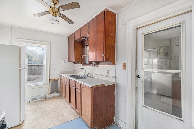 kitchen featuring brown cabinets, freestanding refrigerator, light countertops, and a sink