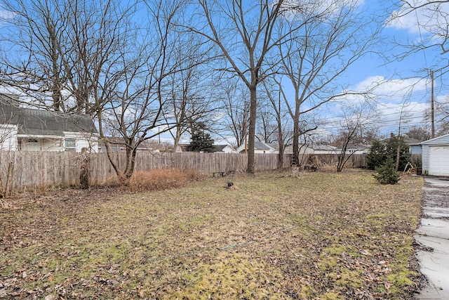 view of yard featuring a garage, an outbuilding, and a fenced backyard