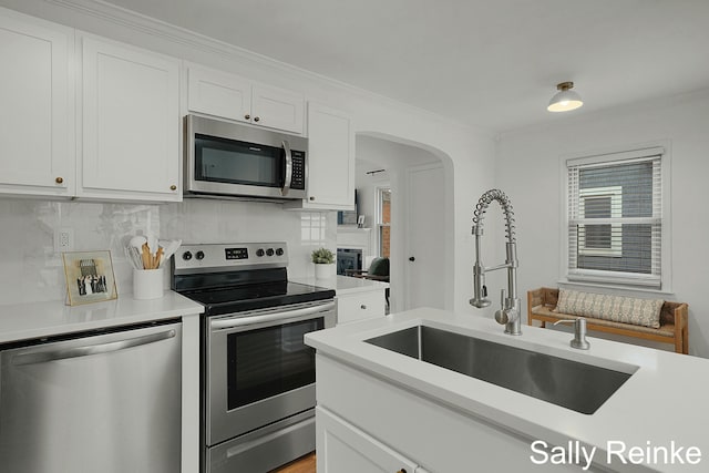 kitchen featuring decorative backsplash, appliances with stainless steel finishes, light countertops, white cabinetry, and a sink