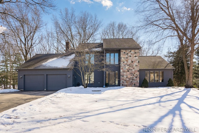 view of front of property featuring driveway, stone siding, a garage, and a chimney