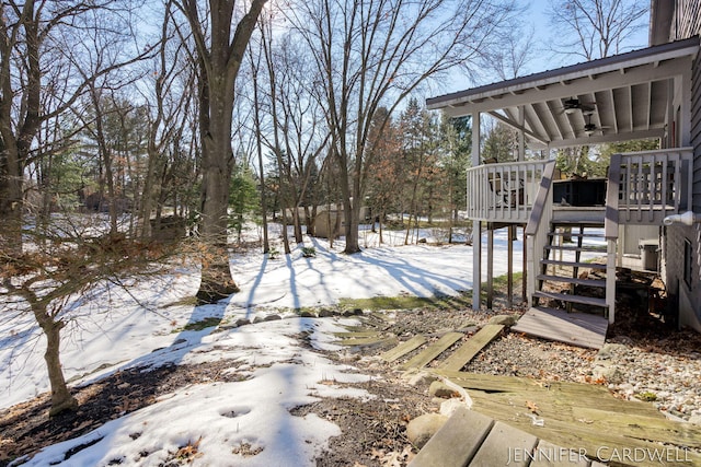 yard layered in snow featuring stairway, a ceiling fan, and a wooden deck