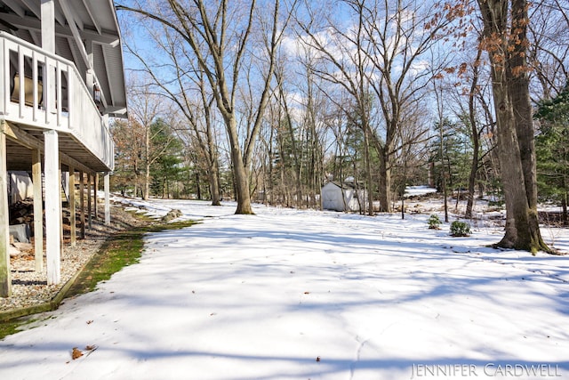 yard covered in snow featuring a storage shed and an outdoor structure