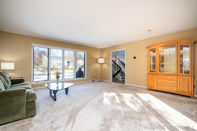 carpeted living area featuring stairs and baseboards