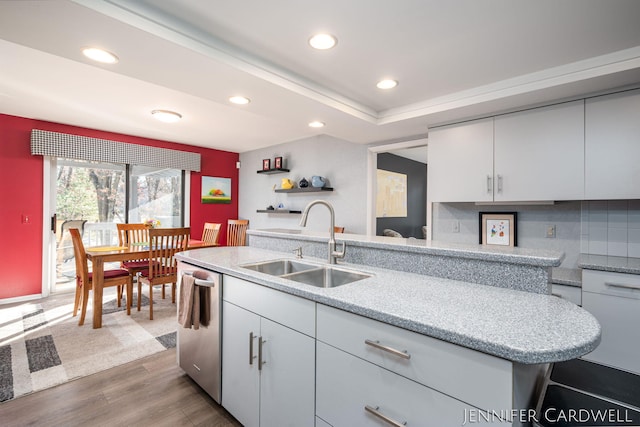 kitchen featuring white cabinets, dishwasher, a sink, and wood finished floors