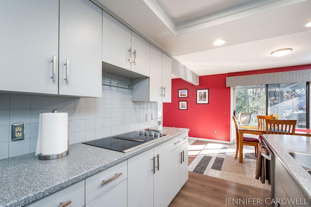 kitchen with tasteful backsplash, dark wood-style flooring, black electric cooktop, light countertops, and white cabinetry