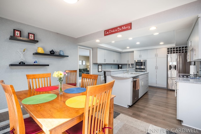 dining area featuring recessed lighting, a raised ceiling, and wood finished floors