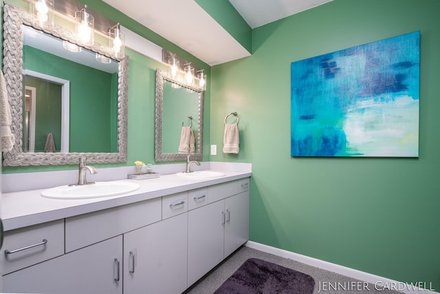 bathroom with double vanity, a sink, and baseboards