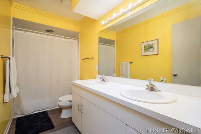 bathroom with ornamental molding, a sink, toilet, and double vanity