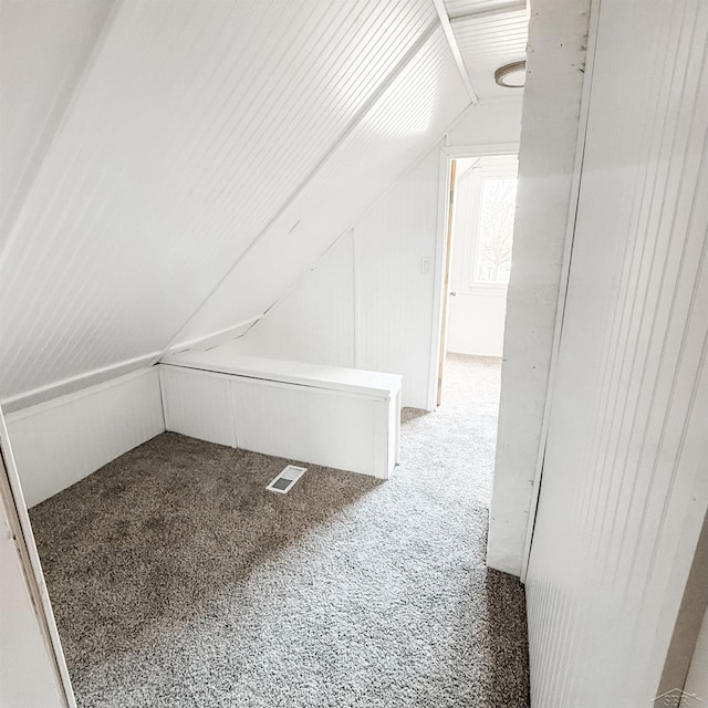 additional living space with vaulted ceiling, visible vents, and light colored carpet