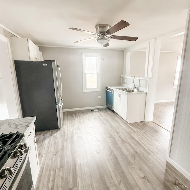 kitchen with light wood finished floors, white cabinetry, appliances with stainless steel finishes, and a sink