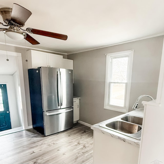 kitchen with a sink, plenty of natural light, freestanding refrigerator, a ceiling fan, and ornamental molding