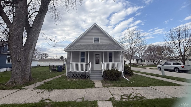 bungalow featuring roof with shingles, a porch, and a front yard