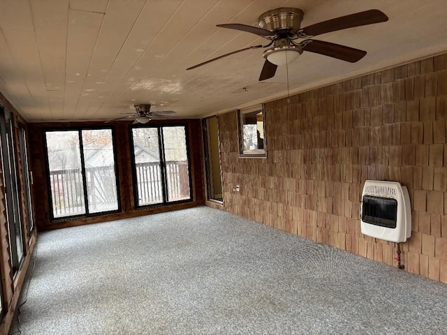 carpeted empty room featuring heating unit, wood walls, and wooden ceiling