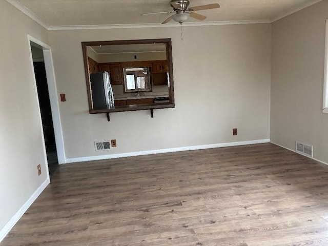 unfurnished room with a ceiling fan, visible vents, crown molding, and wood finished floors