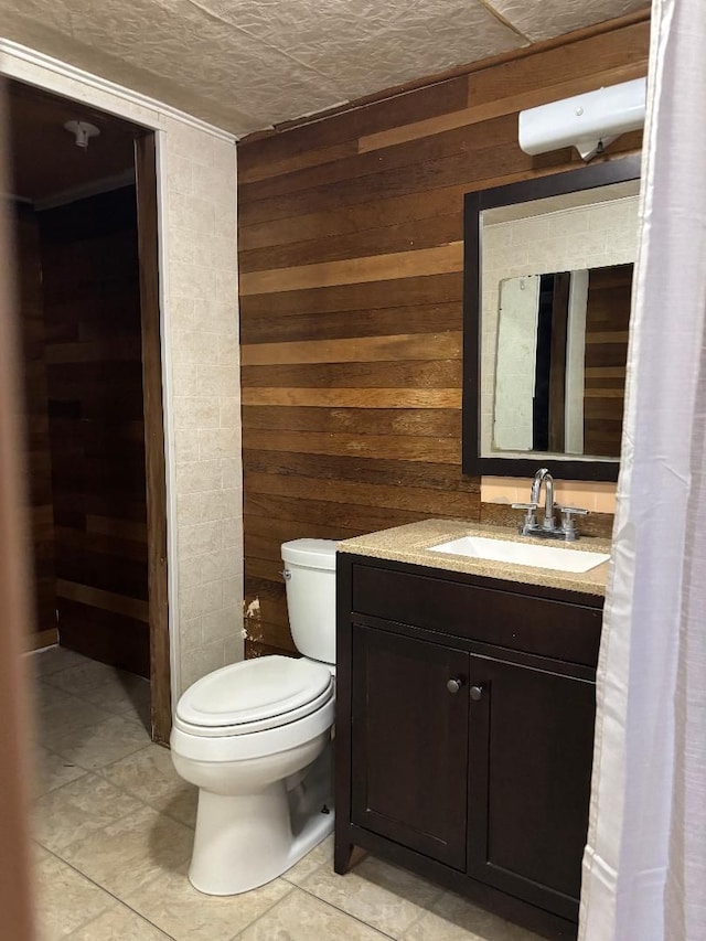 bathroom featuring vanity, toilet, and wooden walls